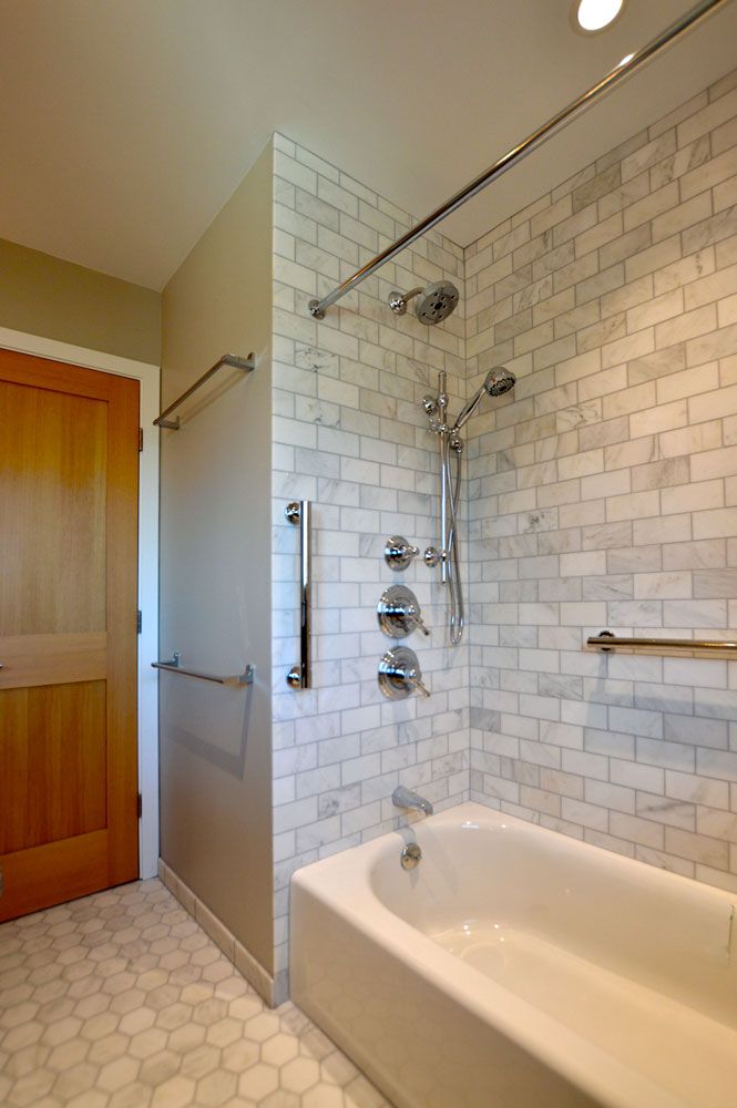 Bathroom remodeling project featuring a marble subway tile shower and tub combo with chrome dual shower fixtures, grab bar, and hexagon tile floor by Craftworks Construction.